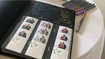 Guests assembling and signing a photo booth scrapbook at a wedding